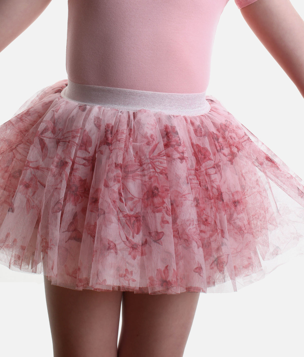 A close-up of a child wearing a pink tulle tutu skirt with a darker pink butterfly pattern and a light pink bodysuit against a white background.